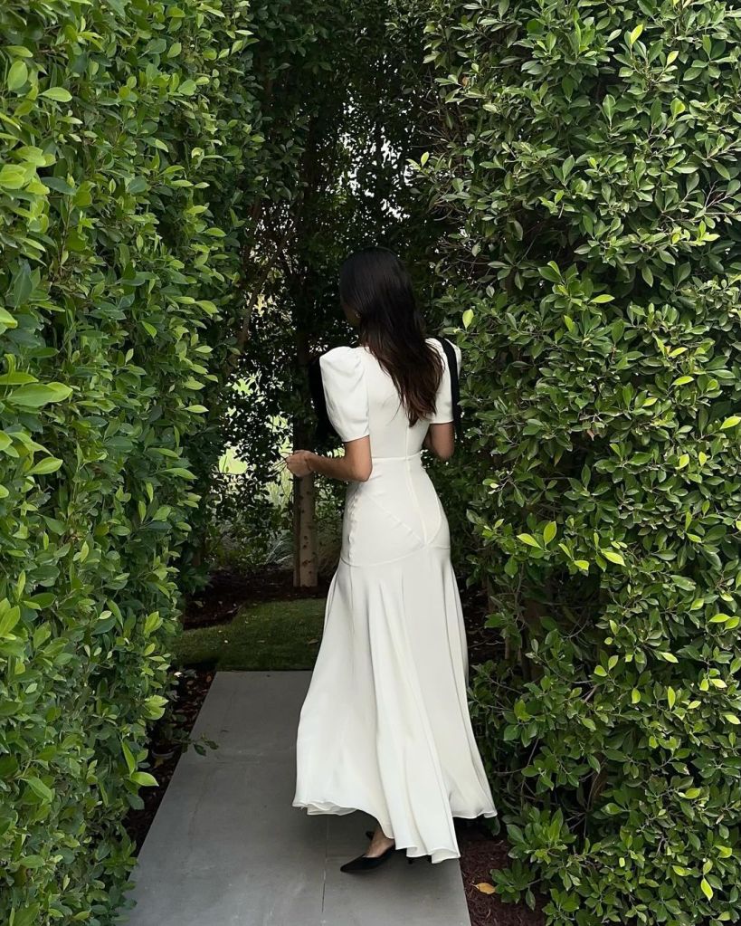 Kendall Jenner in white silk dress with back turned to camera.