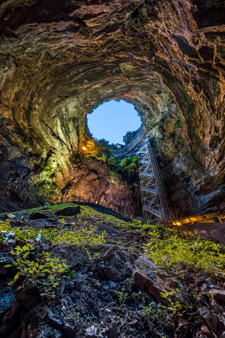 photo looking upwards at the sky from inside a cave