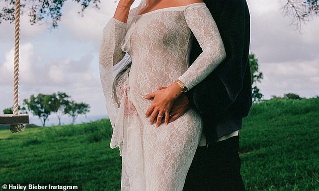 Bieber wore a skintight, long-sleeved white lace dress that came with a matching head scarf to debut her bump to the world