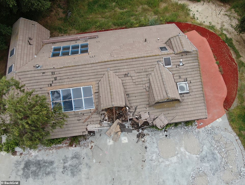 Roof shingles can be seen missing and falling off, while green plants and trees are seemingly overgrown near the front of the main house