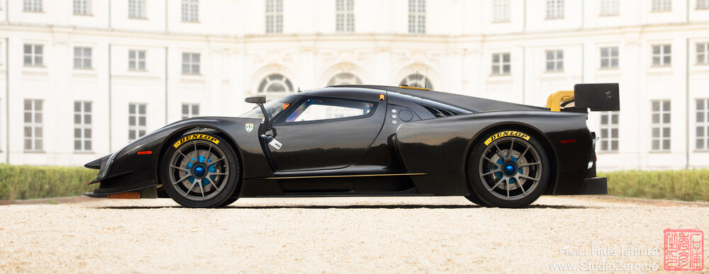 Black SCG 003 parked in front of white building