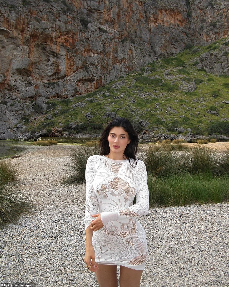 In this image she had on a white lace semi-sheer mini dress while on a rocky beach