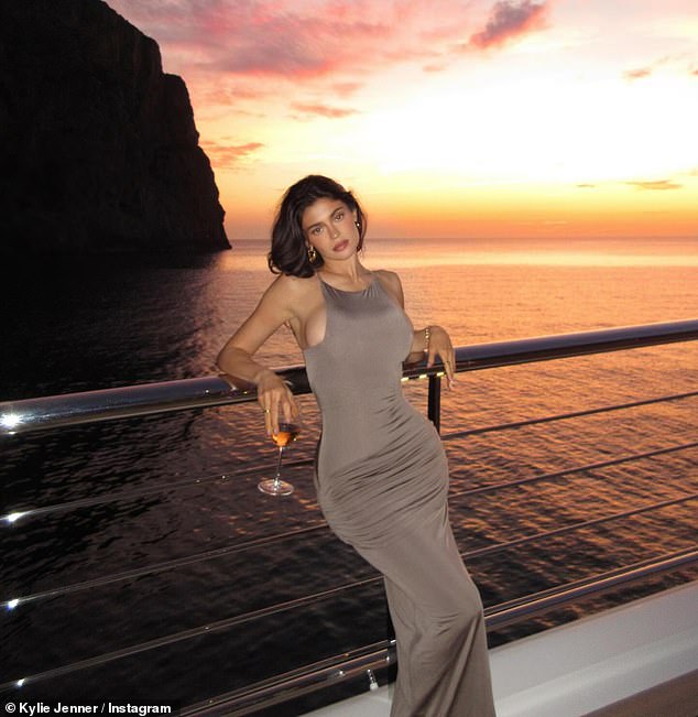 Kylie sported a tan-colored ensemble that clung to her frame on another evening and stopped to take a snap with the colorful sunset in the background