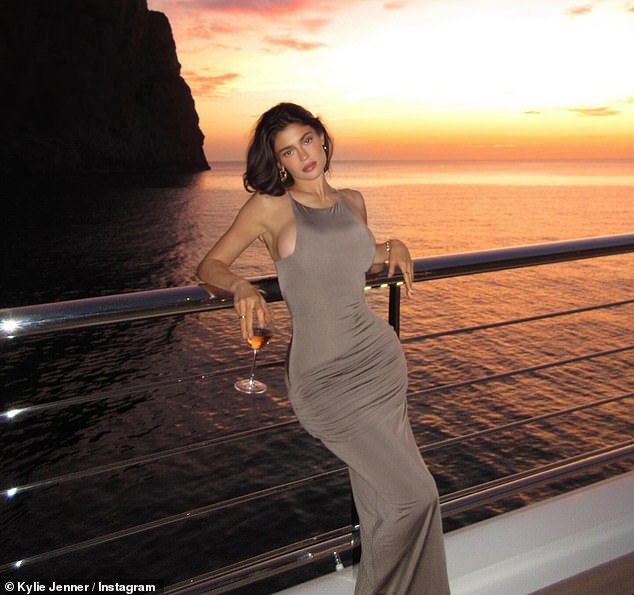 Kylie sported a tan-colored ensemble that clung to her frame during another evening and stopped to take a snap with the colorful sunset in the background