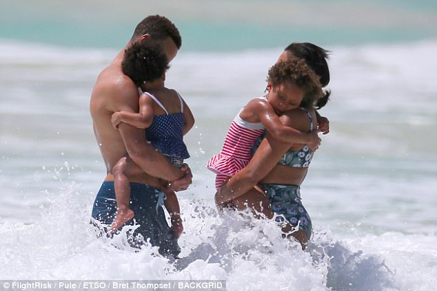 Keeping them safe: The whole family ventured into the water, with Steph gathering up one-year-old Ryan in his arms and Ayesha occasionally doing the same with four-year-old Riley